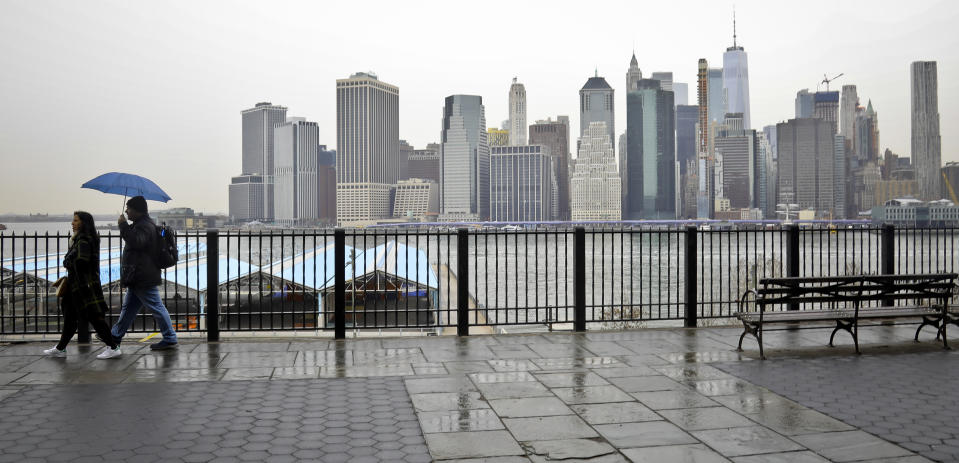 Visitors walk along Brooklyn Heights Promenade during a rainy day Friday April 5, 2019, in New York. The promenade makes up the top deck overhang of a deteriorating Brooklyn-Queens Expressway and the city's plans for repairs has drawn neighborhood protest, since it calls for a temporary six lane highway on the promenade. (AP Photo/Bebeto Matthews)