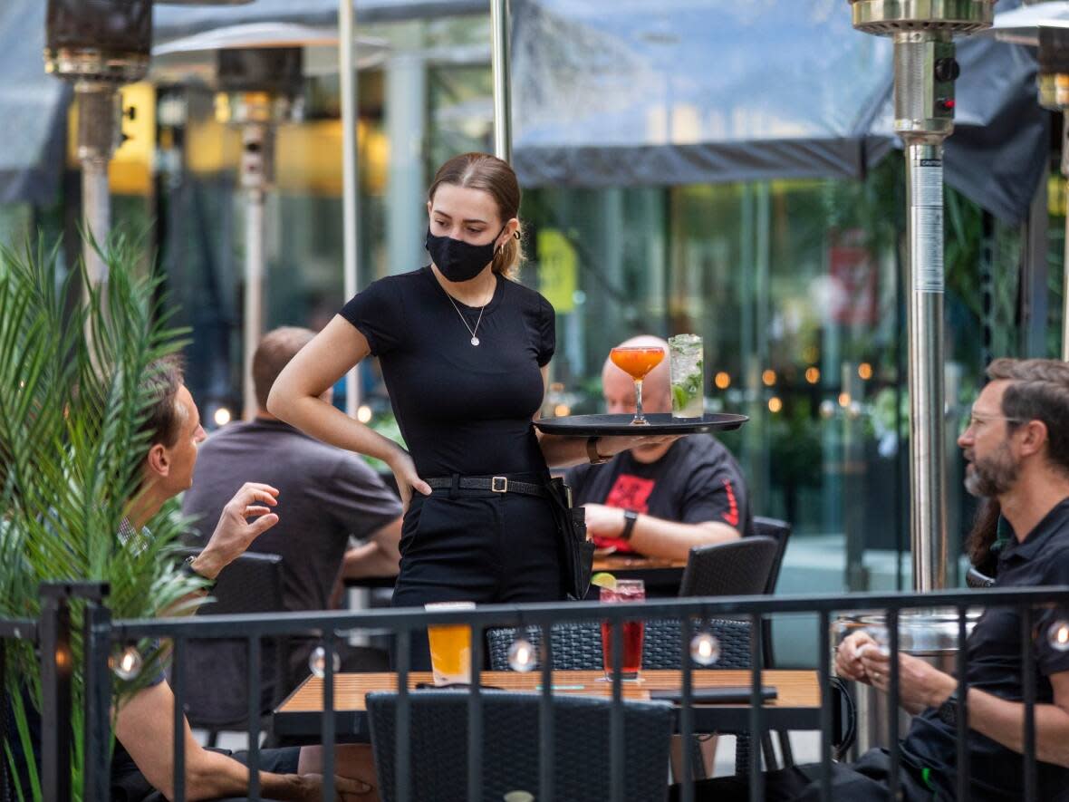 A server takes an order from patrons at a restaurant in downtown Vancouver, British Columbia on Tuesday, June 22, 2021.  (Ben Nelms/CBC - image credit)