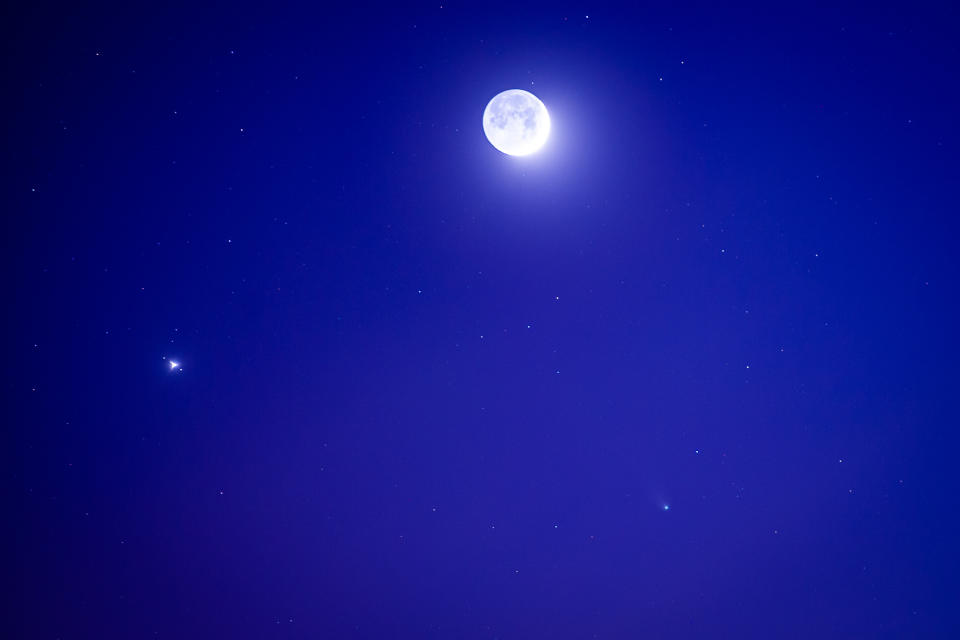 a fuzzy bright orb can be seen in the night sky under a bright moon