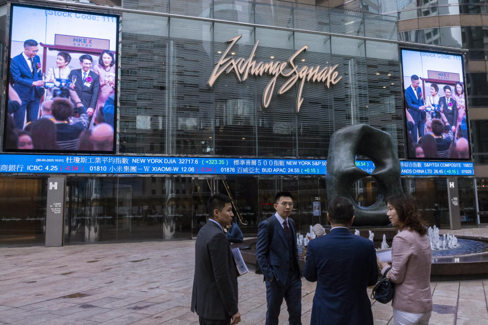 Pedestrians pass by the Hong Kong Stock Exchange electronic screen in Hong Kong, Thursday, March 30, 2023. Asian shares were mixed Thursday following a rally on Wall Street as worries over banks following the collapses of several lenders in recent weeks eased further. (AP Photo/Louise Delmotte)