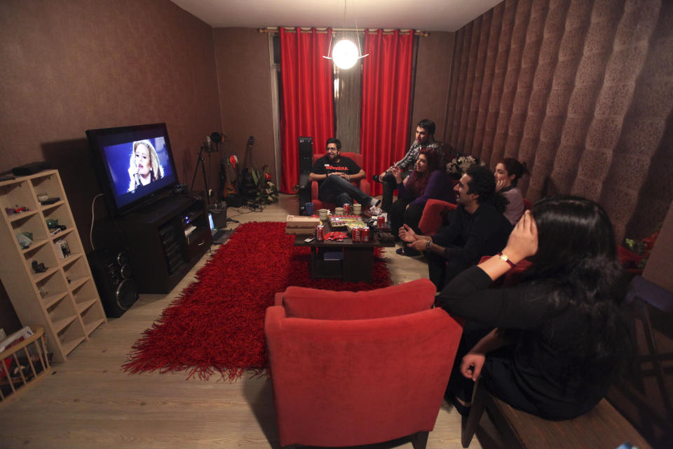 In this picture taken on Monday, Feb. 4, 2013, members of an Iranian band called "Accolade" and their friends watch a performance of British singer Adele, following their training session at the house of one of their members in Tehran, Iran. Headphone-wearing disc jockeys mixing beats. Its an underground music scene that is flourishing in Iran, despite government restrictions. (AP Photo/Vahid Salemi)