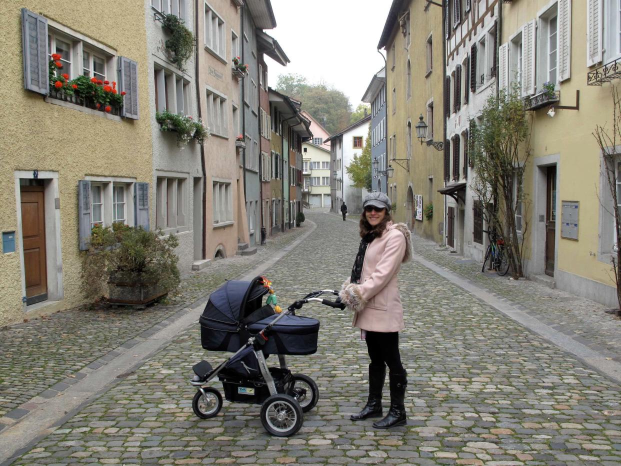 Woman with stroller on cobblestone street in Switzerland