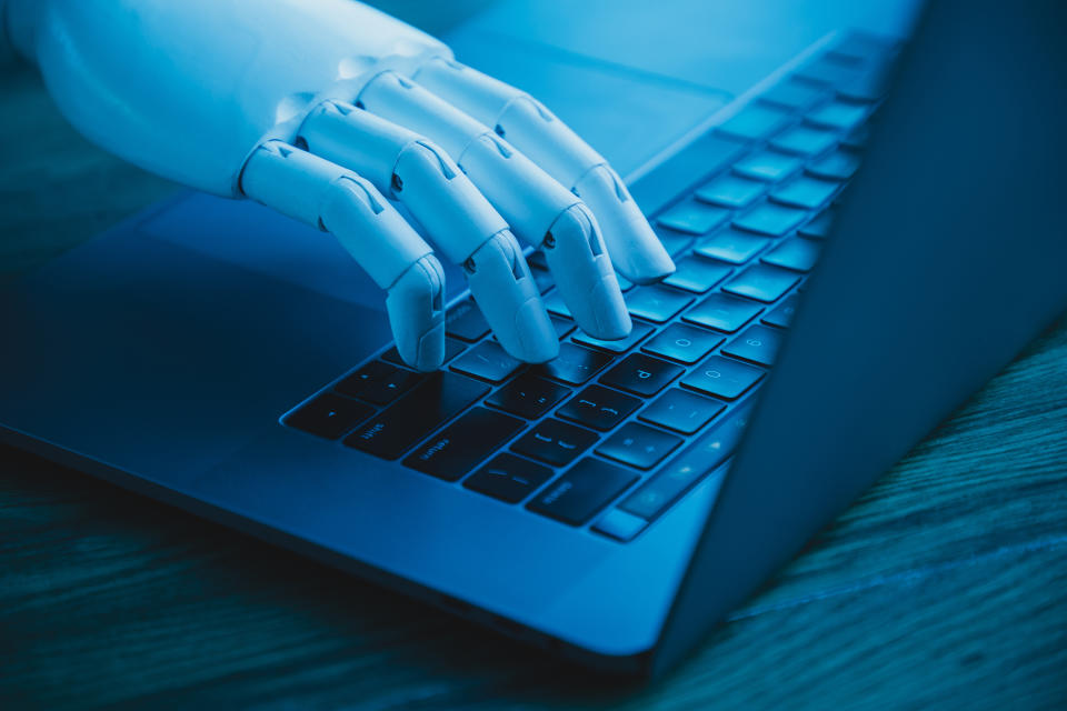 Una mano robótica utiliza un ordenador portátil (concepto de IA que sustituye al trabajador de oficina) (Getty Creative)