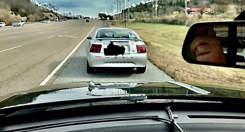 A Mustang is pictured pulled over on a side road by police.