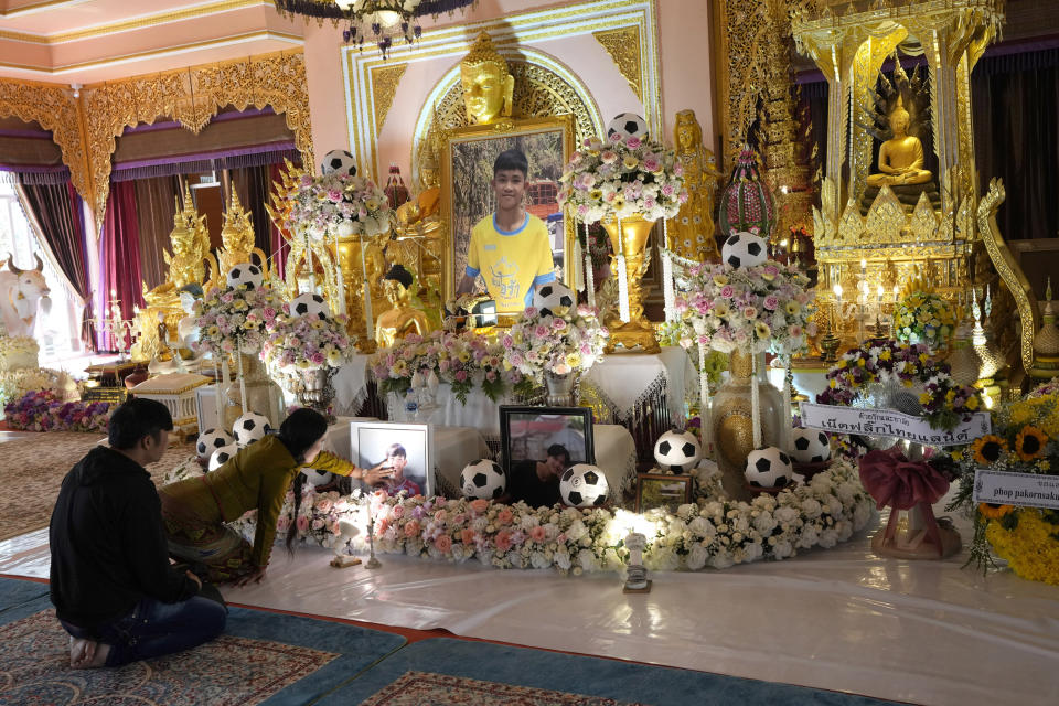 Family members touch portrait of Duangphet Phromthep during a funeral at Wat Phra That Doi Wao temple in Chiang Rai province, Thailand, Sunday, March 5, 2023. The cremated ashes of Duangphet, one of the 12 boys rescued from a flooded cave in 2018, arrived in the far northern Thai province of Chiang Rai on Saturday where final Buddhist rites for his funeral will be held over the next few days following his death in the U.K. (AP Photo/Sakchai Lalit)