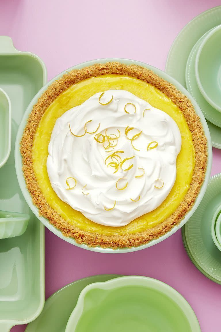 meyer lemon pie in a light green pie dish with whipped cream and lemon zest on top