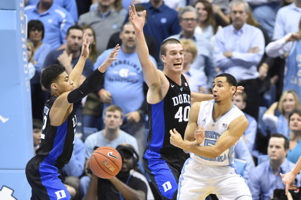 Feb 17, 2016; Chapel Hill, NC, USA; North Carolina Tar Heels guard Marcus Paige (5) passes the ball as Duke Blue Devils guard Derryck Thornton (12) and center Marshall Plumlee (40) defend in the first half at Dean E. Smith Center. Mandatory Credit: Bob Donnan-USA TODAY Sports