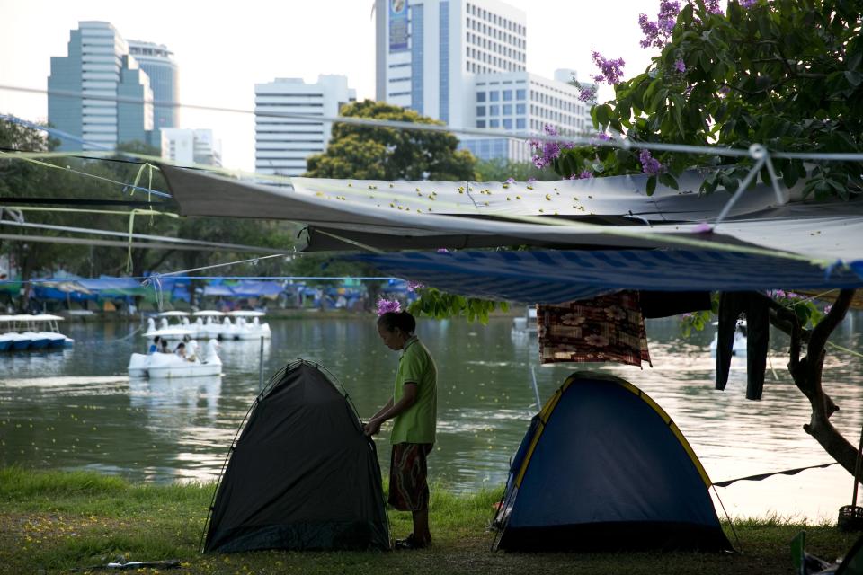 An anti-government protester adjusts her tent in Lumpini Park in downtown Bangkok April 6, 2014. Viewed from above, with it's sea of blue tarpaulin sheets, Bangkok's Lumpini Park looks like a shelter for victims of a natural disaster. Surrounded by skyscrapers and once a haven for joggers, the Thai capital's most famous park has become the temporary home of more than 10,000 supporters of a movement that's been trying for five months to bring down Prime Minister Yingluck Shinawatra. Picture taken April 6, 2014. REUTERS/Darren Whiteside (THAILAND - Tags: POLITICS CIVIL UNREST)