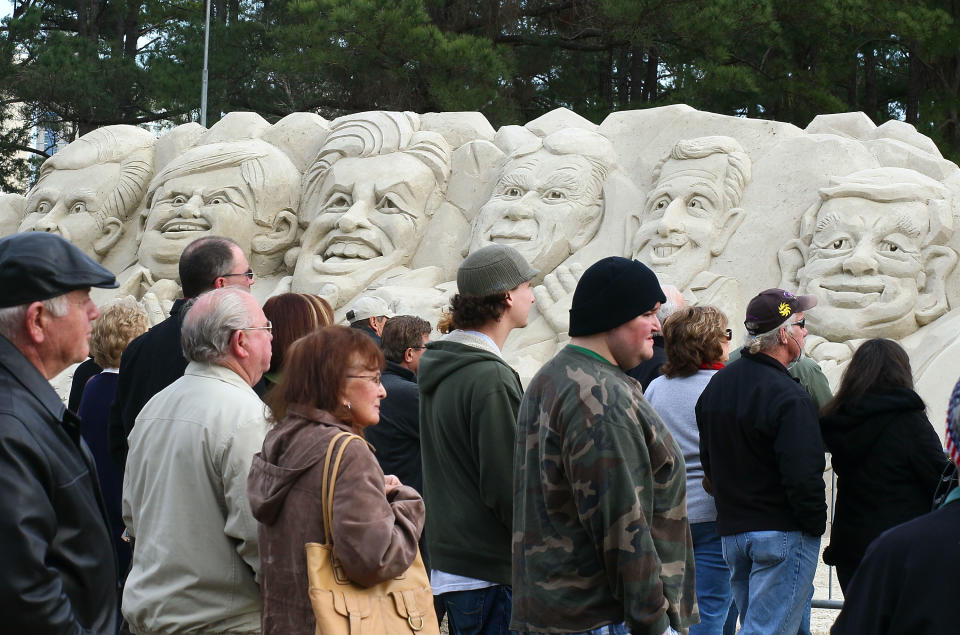 MYRTLE BEACH, SC - JANUARY 16: People stand in front of a sand sculpture depicting Republican presidential candiates (L-R) Mitt Romney, Newt Gingrich, former candidate Jon Huntsman, Rick Perry, Rick Santorum and Ron Paul, in front of the Myrtle Beach Convention Center, on January 16, 2012 in Myrtle Beach, South Carolina. Later tonight all the remaining Republican candidates will participate in a 90 minute debate. (Photo by Mark Wilson/Getty Images)