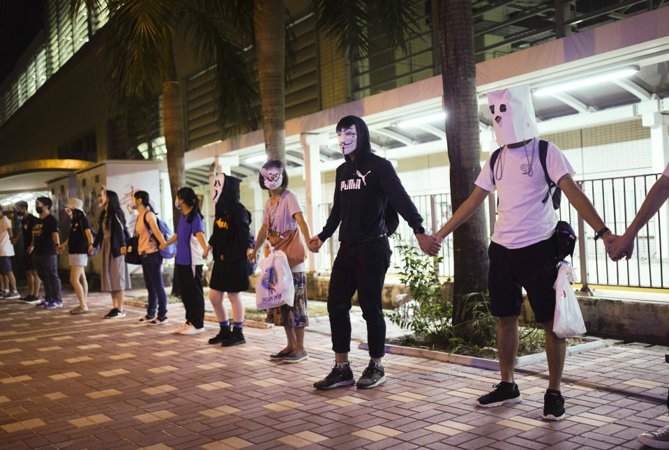 Protesters wear masks in Hong Kong, Friday, Oct. 18, 2019. Hong Kong pro-democracy protesters are donning cartoon/superheroes masks as they formed a human chain across the semiautonomous Chinese city, in defiance of a government ban on face coverings. (AP Photo/Vincent Yu)