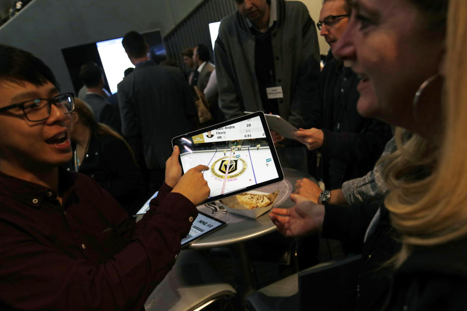 People watch real-time puck and player tracking technology on a tablet during an NHL hockey game between the Vegas Golden Knights and the San Jose Sharks in Las Vegas, Thursday, jan. 10, 2019. The NHL for the first time has tested real-time puck and player tracking in regular-season games with the aim of having it ready for the 2019-20 season. Microchips were added to players’ shoulder pads and fitted inside specially designed pucks for two Vegas Golden Knights home games this week: Tuesday against the New York Rangers and Thursday against the San Jose Sharks. Antennas stationed around the arena tracked the players and the puck through radio frequencies and beamed the data to a suite where league and Players’ Association executives and representatives from 20 teams and various technology firms, sports betting companies and TV rights holders were on hand for the two nights of testing. (AP Photo/John Locher)