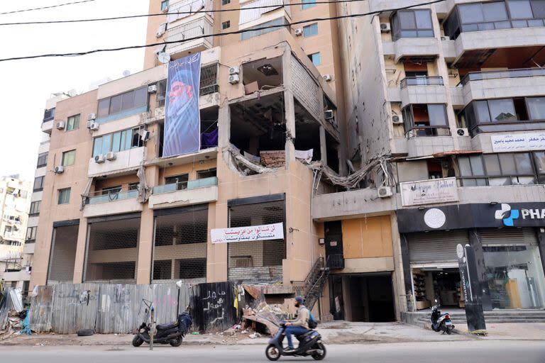 Esta fotografía tomada el 8 de enero de 2024 muestra una pancarta que representa al líder de Hezbollah, Hassan Nasrallah, colgada en el edificio que fue alcanzado por un ataque con aviones no tripulados, matando al número dos de Hamas en un bastión del sur de Beirut de Hezbollah, el 2 de enero de 2024. (Photo by ANWAR AMRO / AFP)