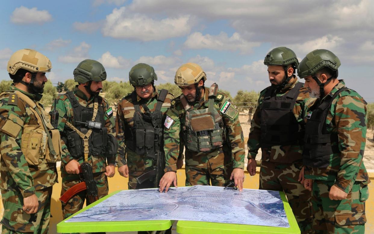 Turkish-backed forces from the Free Syrian Army look at a map during military maneuvers - AP