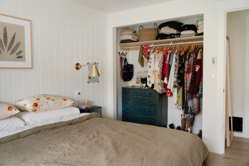 Black painted dresser in neatly organized bedroom closet.