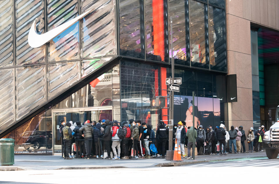 NEW YORK, NEW YORK - NOVEMBER 23: People stand in line outside the Nike store on Fifth Avenue on November 23, 2020 in New York City. The pandemic has caused long-term repercussions throughout the tourism and entertainment industries, including temporary and permanent closures of historic and iconic venues, costing the city and businesses billions in revenue. (Photo by Noam Galai/Getty Images)