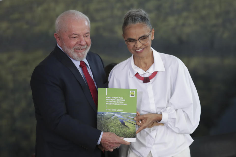 Brazilian President Luiz Inacio Lula da Silva, left, and his Environment Minister Marina Silva pose with a book on preventing and controlling deforestation in the Amazon region on World Environment Day in Brasilia, Brazil, Monday, June 5, 2023. (AP Photo/Gustavo Moreno)