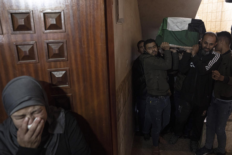 A woman weeps during the funeral of Mohammed al-Shaer, who drowned off the coast of Tunisia, in Rafah, in the southern Gaza Strip, Sunday, Dec. 18, 2022. Thousands of people have joined the funerals of eight young Palestinian men who drowned off the coast of Tunisia nearly two months ago as they tried to sail to new lives in Europe. (AP Photo/Fatima Shbair)