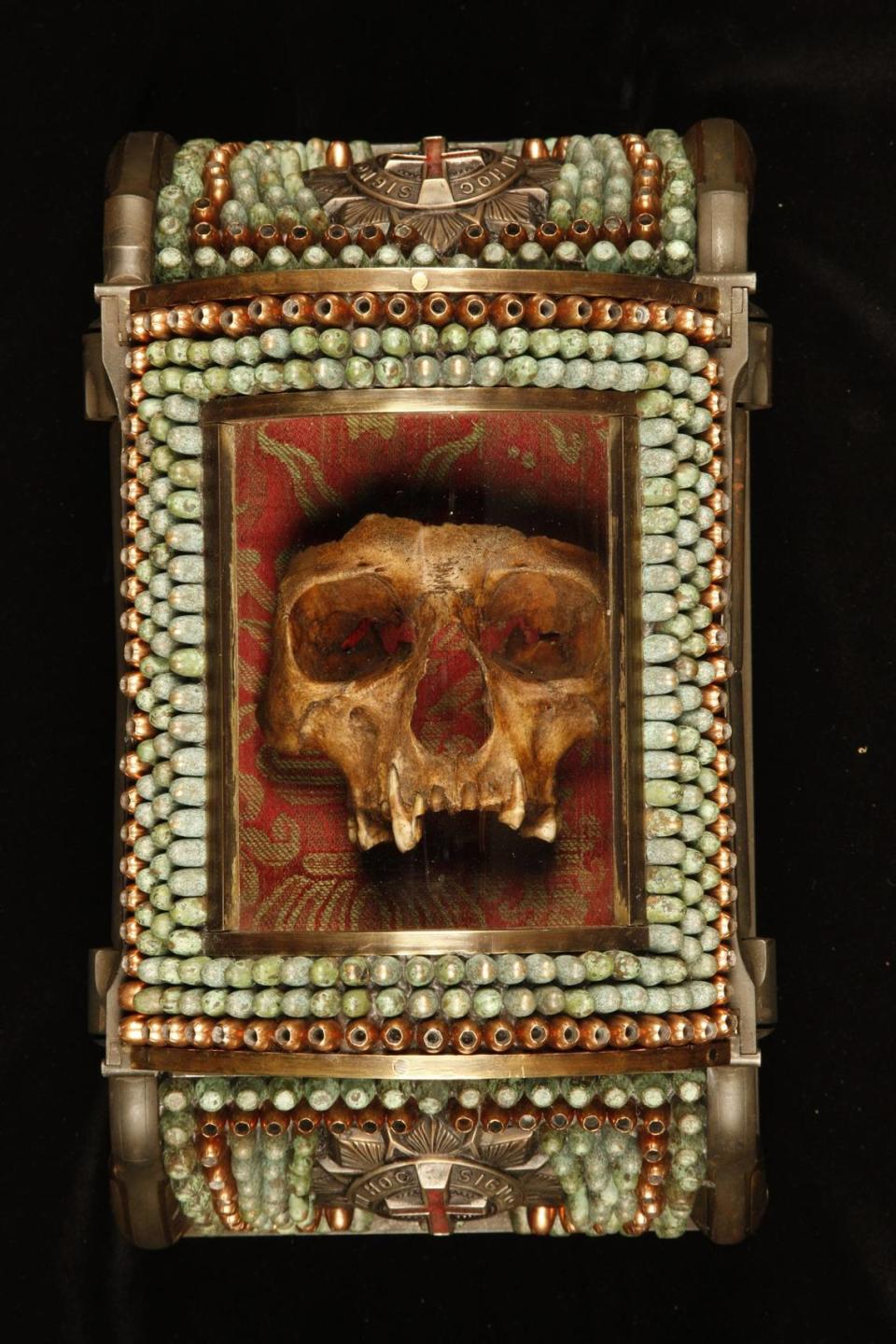 'Casket Reliquary Skull Fragment of Santo Guerro' de Al Farrow se expone en VISU Contemporary en South Beach. La obra incluye un cráneo humano real encerrado en un relicario decorado con balas.