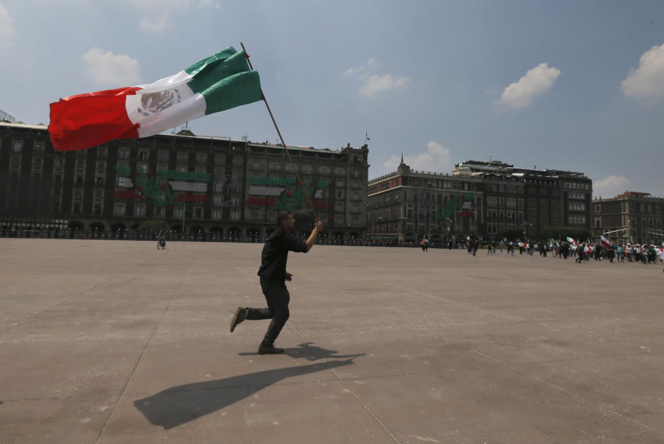 A demonstrator waves a Mexican flag during a protest to demand the resignation of Mexican President Andrés Manuel López Obrador, commonly known by his initials AMLO, in Mexico City's main square the Zocalo, Wednesday, Sept. 23, 2020. (AP Photo/Marco Ugarte)