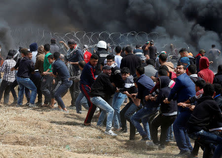 Palestinian demonstrators remove the Israeli barbed wire during clashes with Israeli troops at a protest demanding the right to return to their homeland, at the Israel-Gaza border, east of Gaza City, April 27, 2018. REUTERS/Mohammed Salem