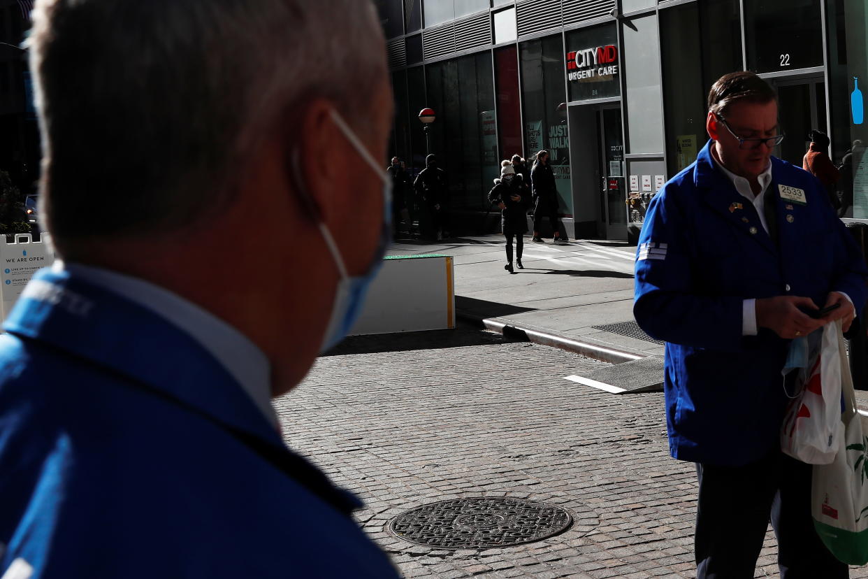 People wait in line outside a CityMD Urgent Care, as the global outbreak of the coronavirus disease (COVID-19) continues, as traders stand outside the New York Stock Exchange (NYSE) in the financial district of New York, U.S., November 19, 2020. REUTERS/Shannon Stapleton