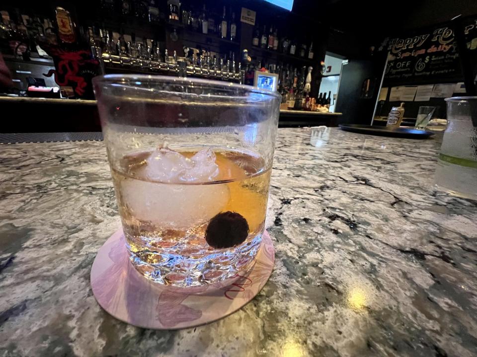 a cocktail in glass on granite counter at bar
