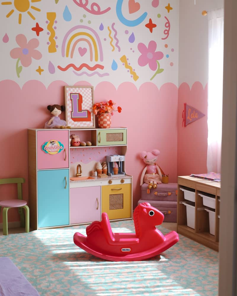 Pink and white kids' room with mural painted walls and lots of colorful accents