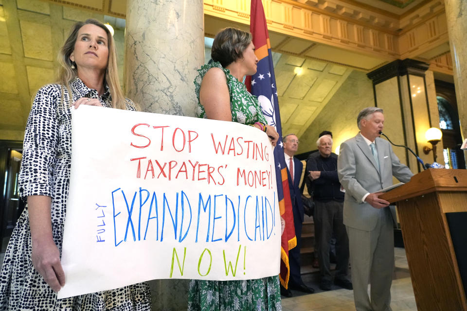 Kathy Knight, left, of Madison, and Kathleen O'Beirne of Ridgeland, hold a sign urging lawmakers to fully fund a Mississippi Medicaid expansion plan, while Jack Reed Jr., a former Tupelo mayor and a long time northeast Mississippi businessman, right, joins a group of small business owners who urged the same during a Tuesday, April 23, 2024, news conference at the state Capitol in Jackson, Miss. (AP Photo/Rogelio V. Solis)