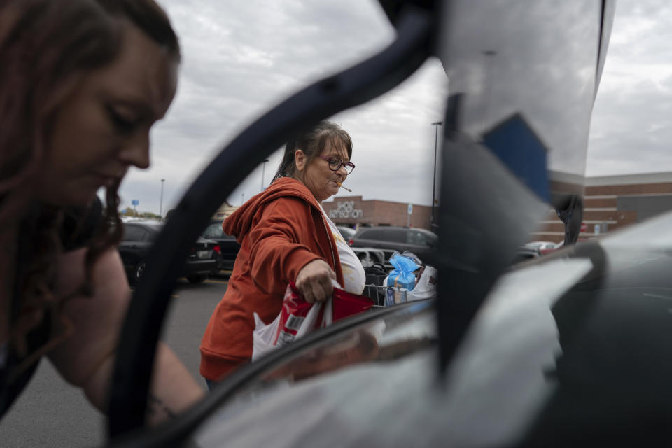 Jesse Johnson, left, of the Family Resource Center helps her client Jodi Ferdinandsen load groceries into the trunk at Walmart in Findlay, Ohio, Thursday, Oct. 12, 2023, before driving her home. Johnson said a peer support worker from the same organization was instrumental in helping her with her early recovery. (AP Photo/Carolyn Kaster)