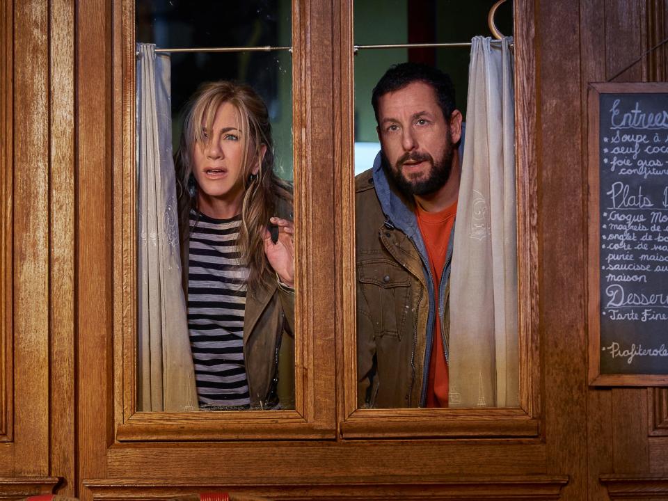 Jennifer aniston and adam sandler looking out a window in a scene from murder mystery 2