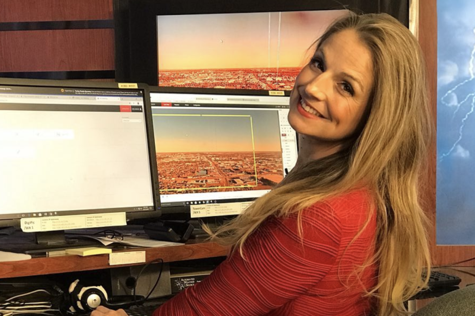 Kelly Plasker sits in front of computer screens at a TV studio. 