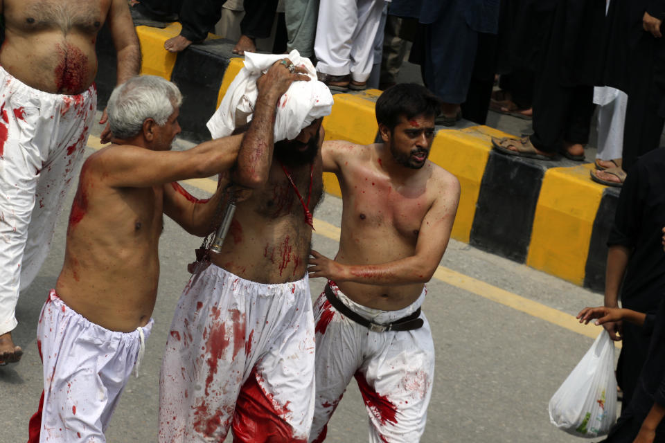 Shiite Muslims escort an injured man after flagellate himself with knifes on chains during a procession to mark Ashoura, in Peshawar, Pakistan, Friday, July 28, 2023. Ashoura is the Shiite Muslim commemoration marking the death of Hussein, the grandson of the Prophet Muhammad, at the Battle of Karbala in present-day Iraq in the 7th century. (AP Photo/Mohammad Sajjad)