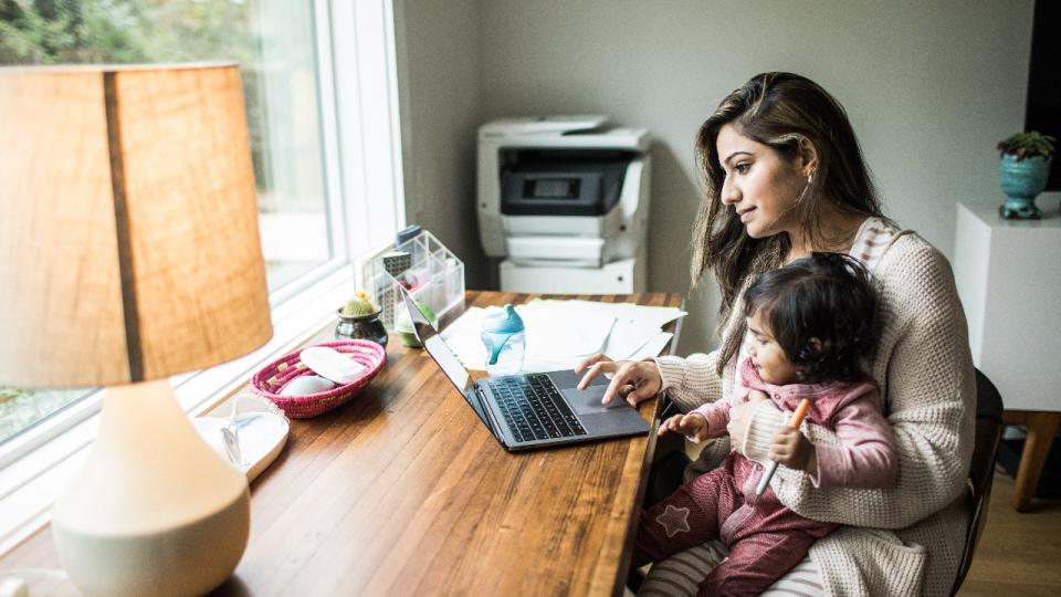 Mother multitasking with toddler daughter in home office