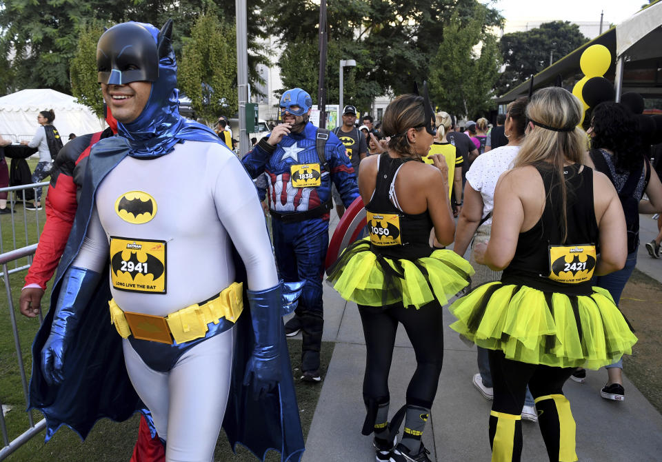 Batman and Captain America walk toward the start line of the Batman Inaugural 5K from the Batman fan experience on Batman's 80th anniversary at Grand Park on Saturday, Sept. 21, 2019, in Los Angeles. (Keith Birmingham/The Orange County Register via AP)