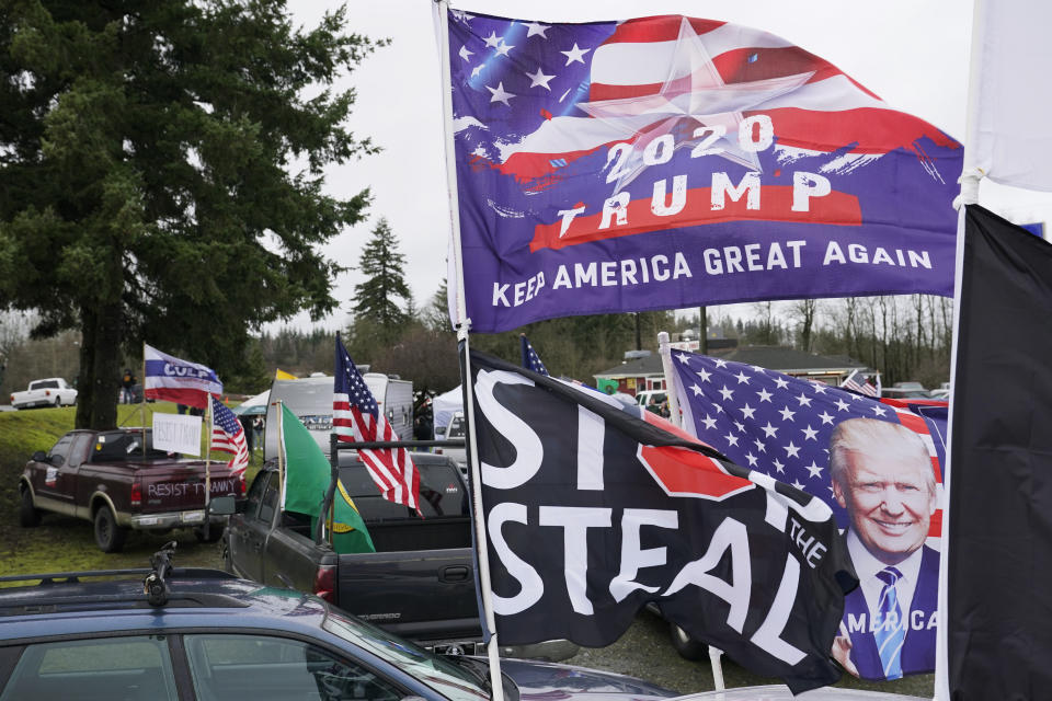 FILE - Flags supporting President Donald Trump and one that reads "Stop the Steal" are displayed during a protest rally, Jan. 4, 2021, at the Farm Boy Drive-In restaurant near Olympia, Wash. A review by The Associated Press in the six battleground states disputed by former President Trump has found fewer than 475 cases of potential voter fraud, a minuscule number that would have made no difference in the 2020 presidential election. Democrat Joe Biden won Arizona, Georgia, Michigan, Nevada, Pennsylvania and Wisconsin and their 79 Electoral College votes by a combined 311,257 votes out of 25.5 million ballots cast for president. (AP Photo/Ted S. Warren, file)