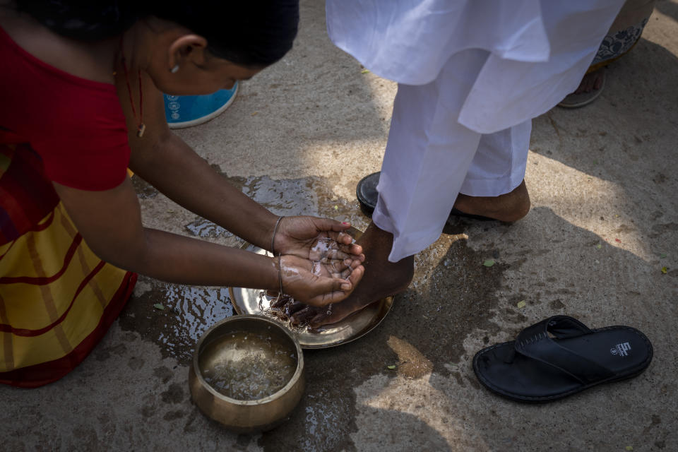 A tribes woman washes the feet of Salkhan Murmu, a former lawmaker and community activist, a traditional custom among tribespeople to welcome guests as he arrives during an awareness campaign to demand recognition of Sarna Dharma as a religion in village Guduta, in the eastern Indian state of Odisha, Oct. 21, 2022. Murmu, who also adheres to Sarna Dharma, is at the center of the protests pushing for government recognition of his religion. His sit-in demonstrations in several Indian states have drawn crowds of thousands. (AP Photo/Altaf Qadri)