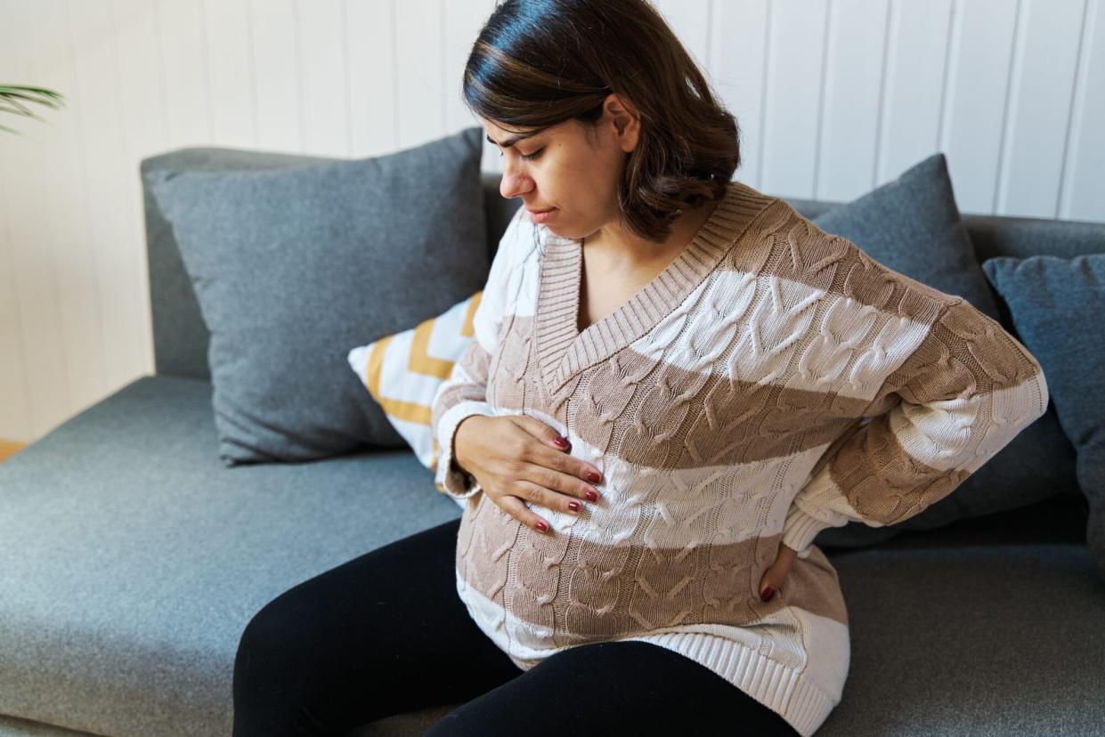 pregnant person holding stomach and back