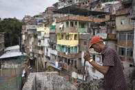 Resident M.C. Bum looks down from the balcony where residents say Douglas Rafael da Silva Pereira fell to the spot where his body was found in the Pavao Pavaozinho slum of Rio de Janeiro, Brazil, Wednesday, April 23, 2014. On Tuesday night, angry residents who blame police for his death set fires and showered homemade explosives and glass bottles onto a busy avenue in the city's main tourist zone following the killing of the popular local figure. (AP Photo/Felipe Dana)