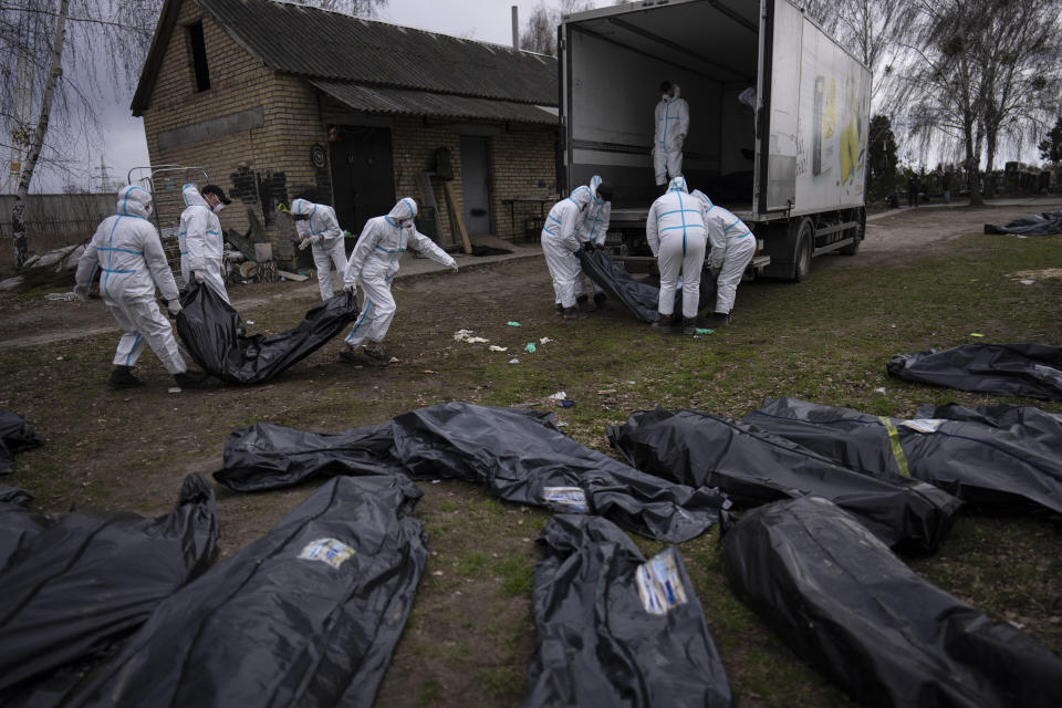FILE - Volunteers load bodies of civilians killed in Bucha onto a truck to be taken to a morgue for investigation, in the outskirts of Kyiv, Ukraine, Tuesday, April 12, 2022. Russian soldiers in intercepted phone conversations called their sweeps of Bucha and other towns “zachistka” – cleansing. They hunted people on lists prepared by their intelligence services and went door to door to identify and neutralize potential threats. When Russian soldiers unable to reach Kyiv faced mounting losses, they became more erratic, conducting sweeps with rising levels of sometimes drunken violence. (AP Photo/Rodrigo Abd, File)