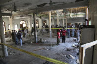 Rescue workers and police officers examine the site of a bomb explosion in an Islamic seminary in Peshawar, Pakistan, Tuesday, Oct. 27, 2020. A powerful bomb blast ripped through the Islamic seminary on the outskirts of the northwest Pakistani city of Peshawar on Tuesday morning, killing some students and wounding dozens others, police and a hospital spokesman said. (AP Photo/Muhammad Sajjad)