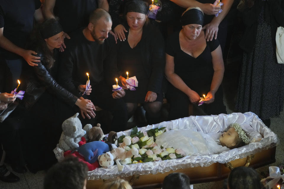 Relatives and friends pay their last respects to Liza, a 4-year-old girl killed by a Russian attack, during a mourning ceremony in an Orthodox church in Vinnytsia, Ukraine, Sunday, July 17, 2022. Wearing a blue denim jacket with flowers, Liza was among 23 people killed, including 2 boys aged 7 and 8, in Thursday's missile strike in Vinnytsia. Her mother, Iryna Dmytrieva, was among the scores injured. (AP Photo/Efrem Lukatsky)