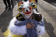 A "La Diablada" dancer embraces a girl during a celebration in honor of the Virgin del Carmen, patron saint of Chile, in Santiago, Chile, Saturday, July 16, 2022. Hundreds of cowboys in woolen ponchos and families on wooden horse carts lined up to receive a priest's blessing in the huge esplanade in front of the National Sanctuary of Maipu on Saturday afternoon. (AP Photo/Esteban Felix)