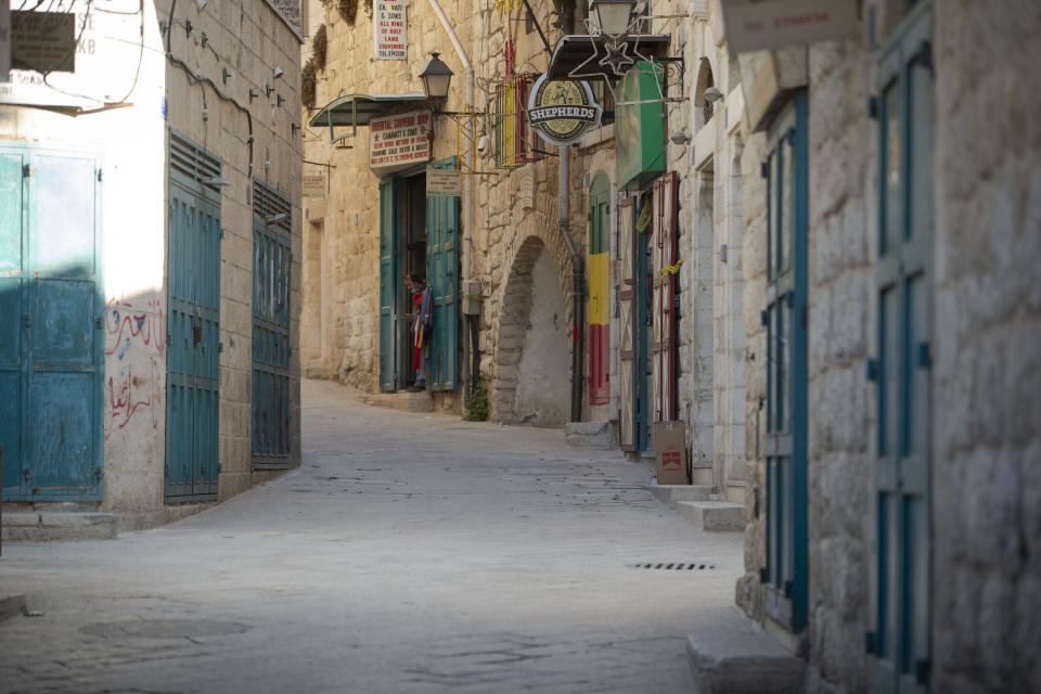 A Palestinian vendor stands in front of his shop near the Church of the Nativity, traditionally believed to be the birthplace of Jesus Christ, in the West Bank City of Bethlehem, Monday, Nov. 23, 2020. Normally packed with tourists from around the world at this time of year, Bethlehem resembles a ghost town – with hotels, restaurants and souvenir shops shuttered by the pandemic. (AP Photo/Majdi Mohammed)