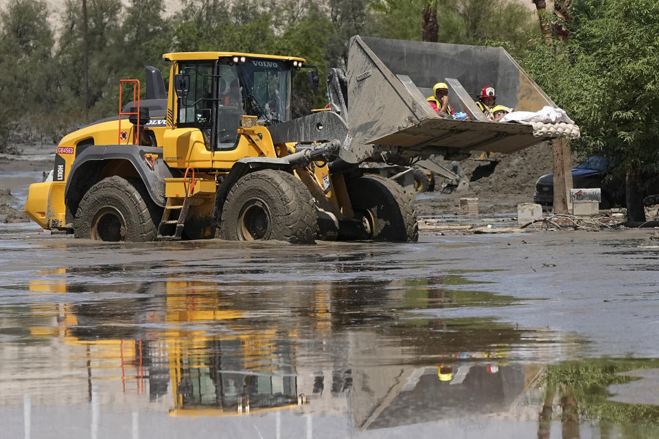 Firefighters use a skip loader to rescue a person from an assisted living center after the street was flooded with mud Monday, Aug. 21, 2023, in Cathedral City, Calif. Forecasters said Tropical Storm Hilary was the first tropical storm to hit Southern California in 84 years, bringing the potential for flash floods, mudslides, isolated tornadoes, high winds and power outages. (AP Photo/Mark J. Terrill)