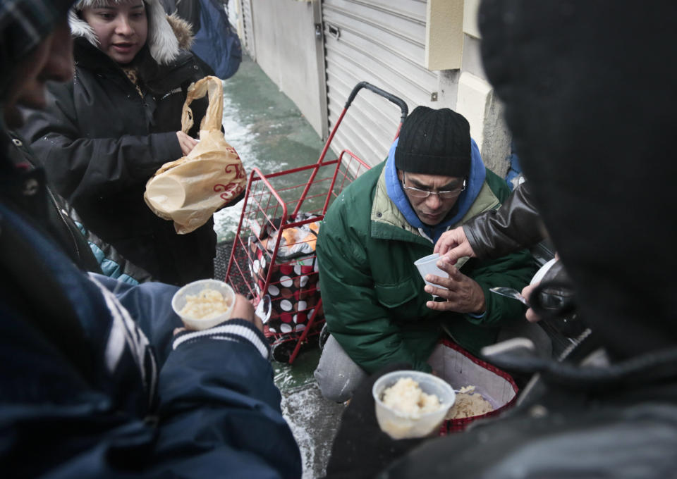 Day laborers gather as Natalia Navas, second from left, a coordinator from New Immigrant Community Empowerment (NICE) organization, distributes hot rice pudding on Tuesday, Dec. 17, 2013 in Queens, N.Y. Non profit labor organizations such as NICE, which opened the new Queens workers center in its Jackson Heights offices, are organizing day laborers to improve working conditions. (AP Photo/Bebeto Matthews)