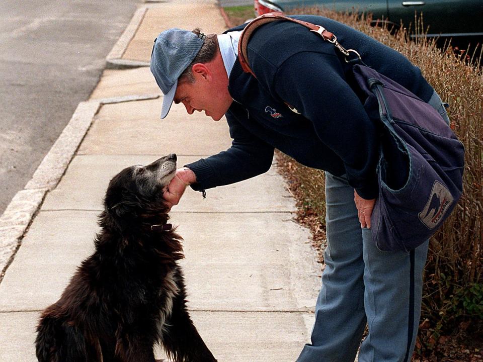 A mailman pets a dog