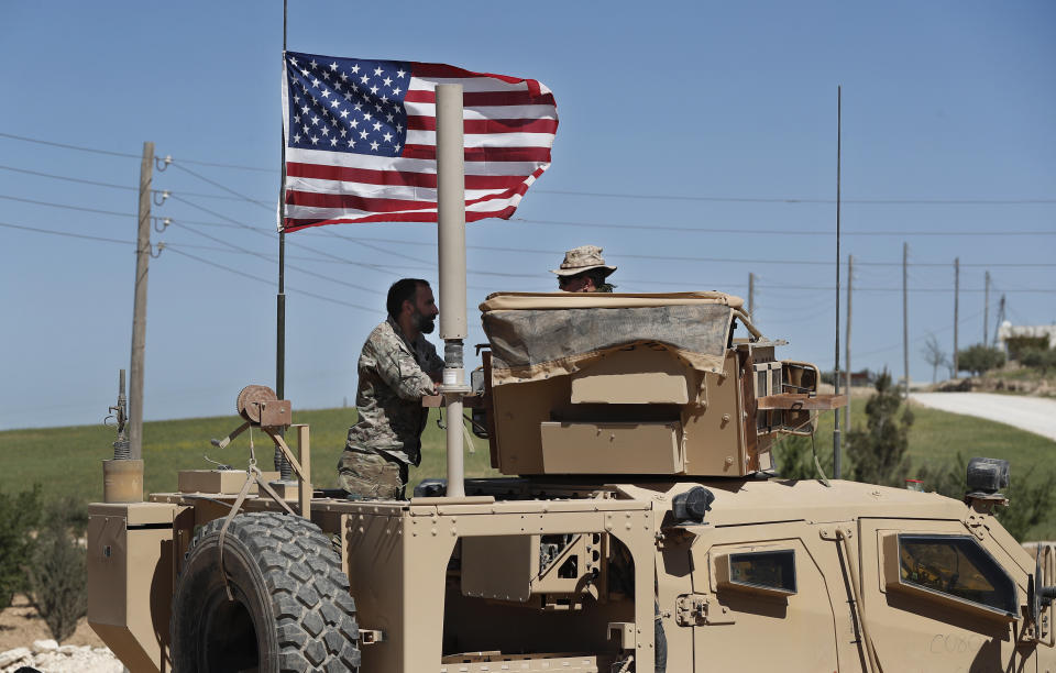 In this April 4, 2018 photo, a U.S-backed Syrian Manbij Military Council soldier, left, speaks with a U.S. soldier, at a U.S. position near the tense front line with Turkish-backed fighters, in Manbij town, north Syria. President Donald Trump's decision to withdraw troops from Syria has rattled Washington's Kurdish allies, who are its most reliable partner in Syria and among the most effective ground forces battling the Islamic State group. Kurds in northern Syria said commanders and fighters met into the night, discussing their response to the surprise announcement Wednesday, Dec. 20, 2018. (AP Photo/Hussein Malla)