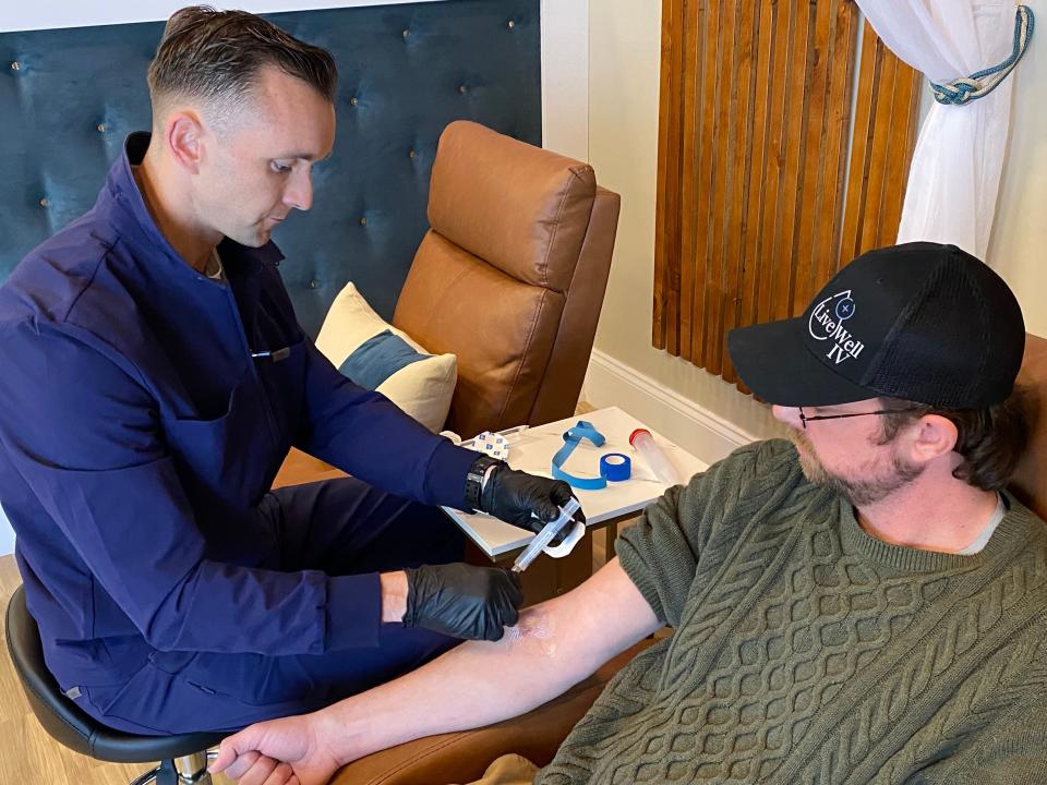 Joseph Matrisciano sets up IV hydration therapy into the arm of employee Matthew Iafrate.