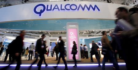 People walk past Qualcomm's stand during the Mobile World Congress in Barcelona, Spain in this February 24, 2016, file photo. REUTERS/Albert Gea