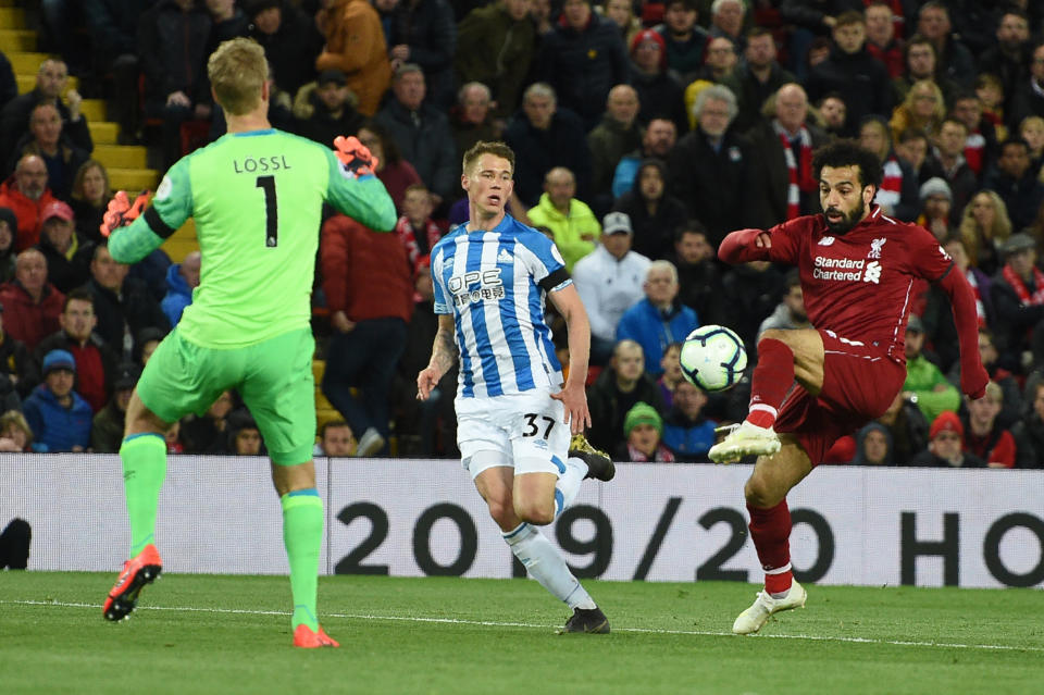 Liverpool's Egyptian midfielder Mohamed Salah (R) scores the team's third goal during the English Premier League football match between Liverpool and Huddersfield at Anfield in Liverpool, north west England on April 26, 2019. (Photo by Oli SCARFF / AFP) / RESTRICTED TO EDITORIAL USE. No use with unauthorized audio, video, data, fixture lists, club/league logos or 'live' services. Online in-match use limited to 120 images. An additional 40 images may be used in extra time. No video emulation. Social media in-match use limited to 120 images. An additional 40 images may be used in extra time. No use in betting publications, games or single club/league/player publications. /         (Photo credit should read OLI SCARFF/AFP/Getty Images)